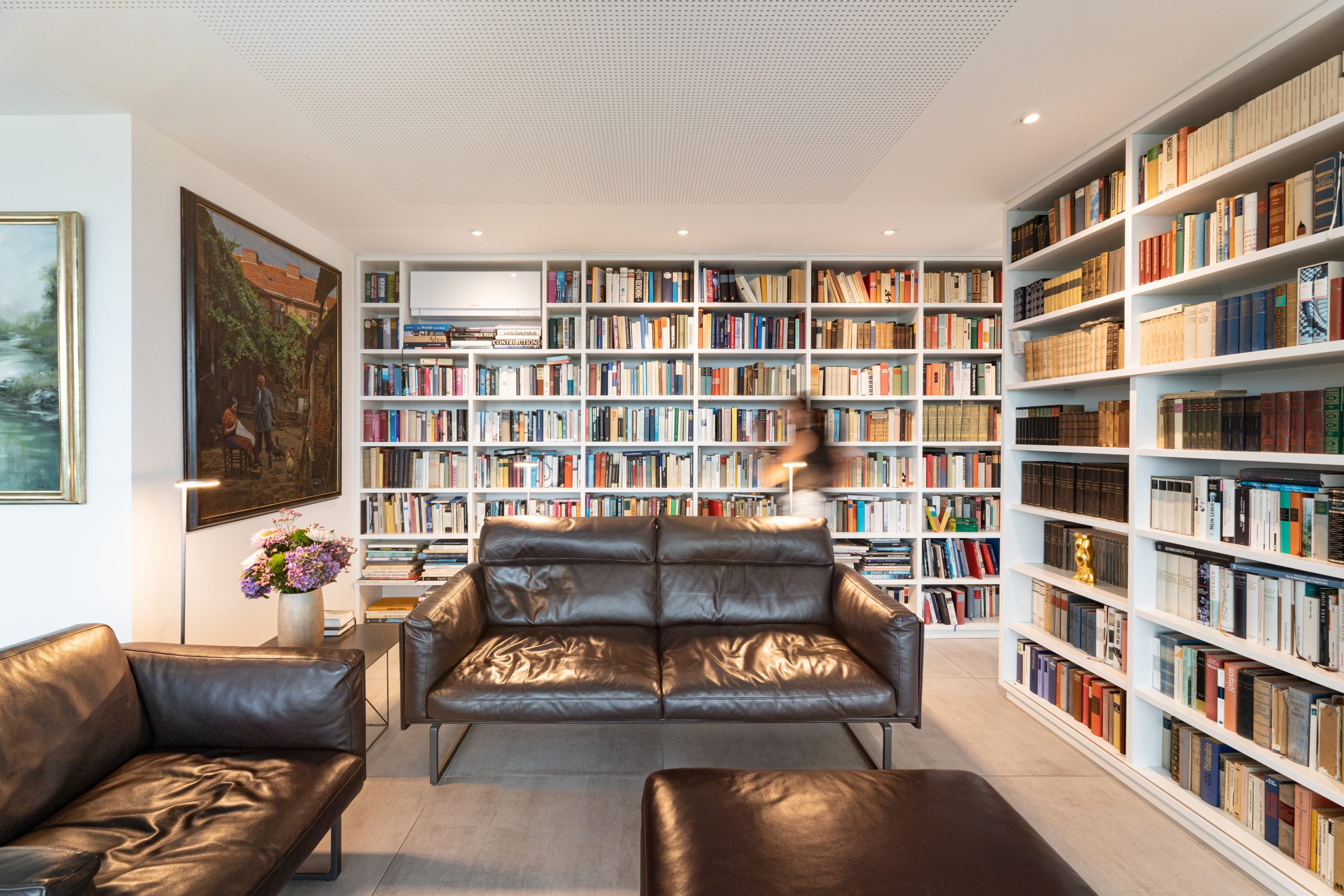 Moderne wandfüllende Bibliothek mit Kunst vom Boden bis zur Decke