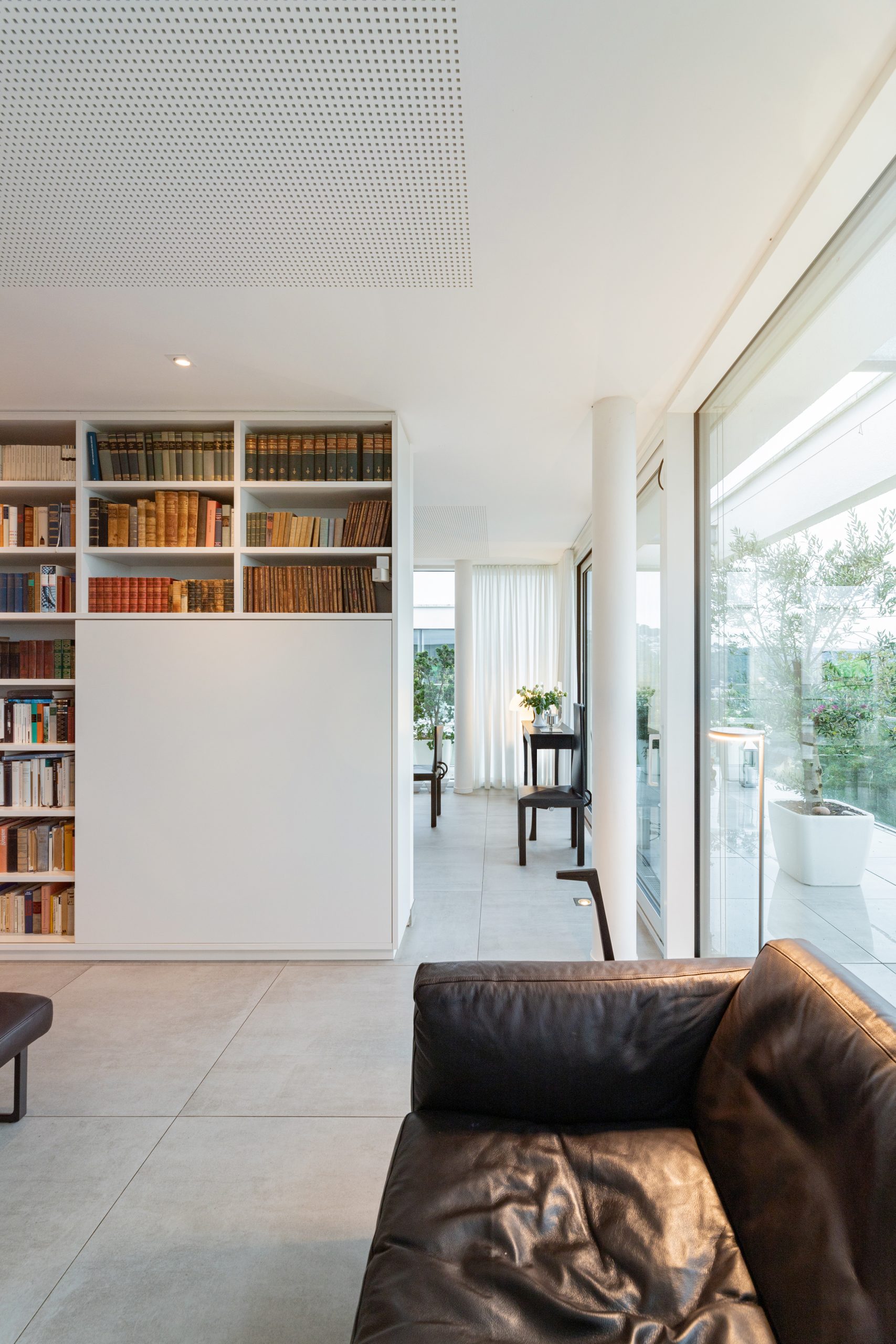 Moderne wandfüllende Bibliothek mit Kunst und verstecktem TV vom Boden bis zur Decke als Raumteiler