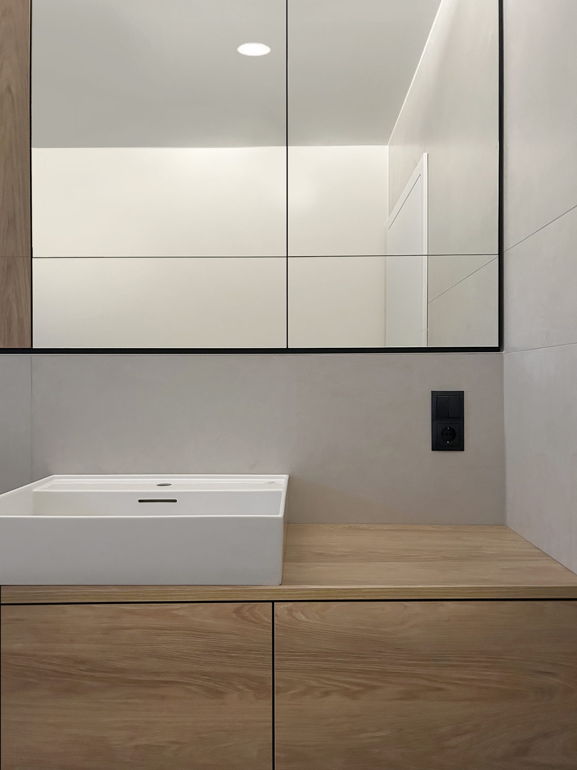 Maßgeschneiderte Innenarchitektur mit Atra Türen von Griffwerk und Laufen Waschtischen mit Hans Grohe Armaturen. Eleganter Spiegelschrank mit viel Stauraum und stilvollem Design für Ihr Badezimmer.