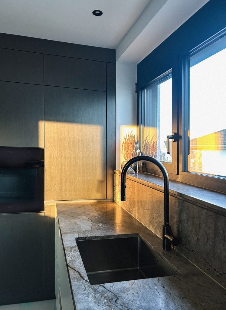 Edle Natursteinküche mit Hochschränken in Steel-Optik – funktional und detailreich gestaltet für zeitgemäße Innenarchitektur.