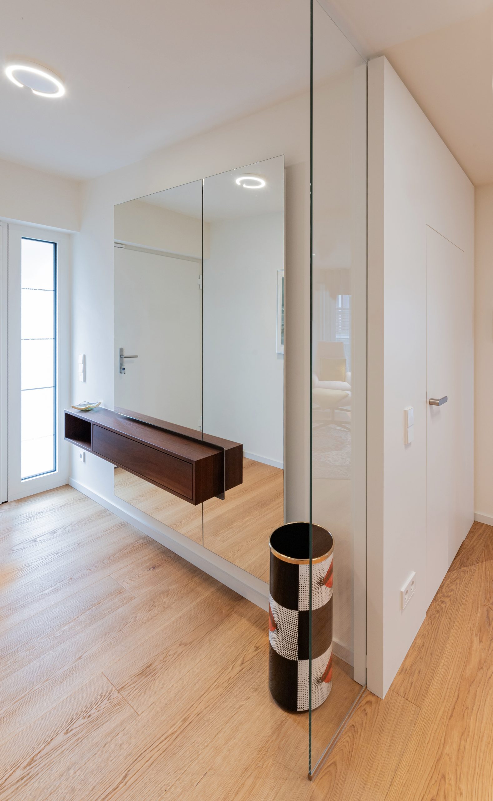 Akzente von Fornasetti bringen eine spielerische, kunstvolle Note in den Raum, der von klaren Linien und edlen, massiven Materialien geprägt ist. Spiegel, Massivholz und eine schlichte, präzise Beleuchtung schaffen eine ruhige Bühne, auf der die Fornasetti-Elemente ihre volle Wirkung entfalten und die Innenarchitektur aufwerten.