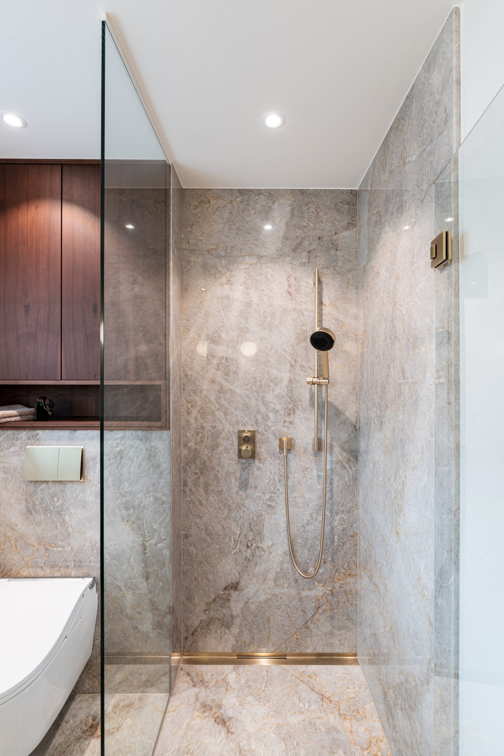 Edler Naturstein mit Tiefe und transparenter Struktur bildet die Grundlage des Designs. Präzise gefertigte Metallarmaturen in hochwertiger Premium-Finish-Ausführung setzen moderne Akzente. Massives Holz und großzügige Designerleuchten ergänzen das Interieur und schaffen eine ruhige, hochwertige Atmosphäre mit klaren Linien und zeitloser Eleganz.