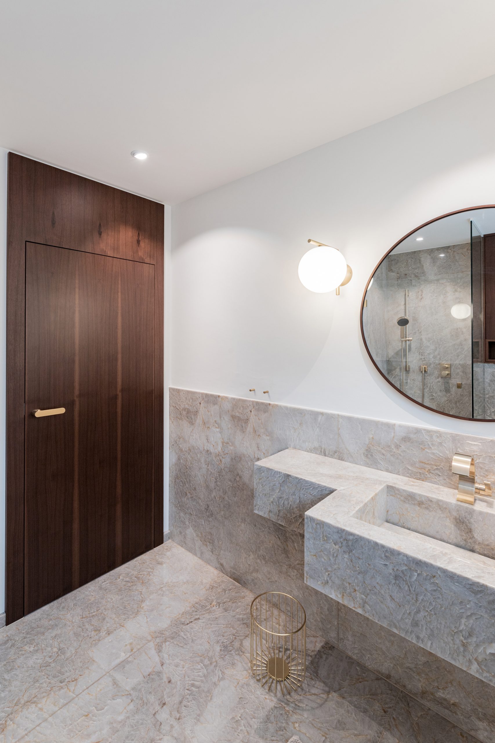 Edler Naturstein mit Tiefe und transparenter Struktur bildet die Grundlage des Designs. Präzise gefertigte Metallarmaturen in hochwertiger Premium-Finish-Ausführung setzen moderne Akzente. Massives Holz und großzügige Designerleuchten ergänzen das Interieur und schaffen eine ruhige, hochwertige Atmosphäre mit klaren Linien und zeitloser Eleganz.