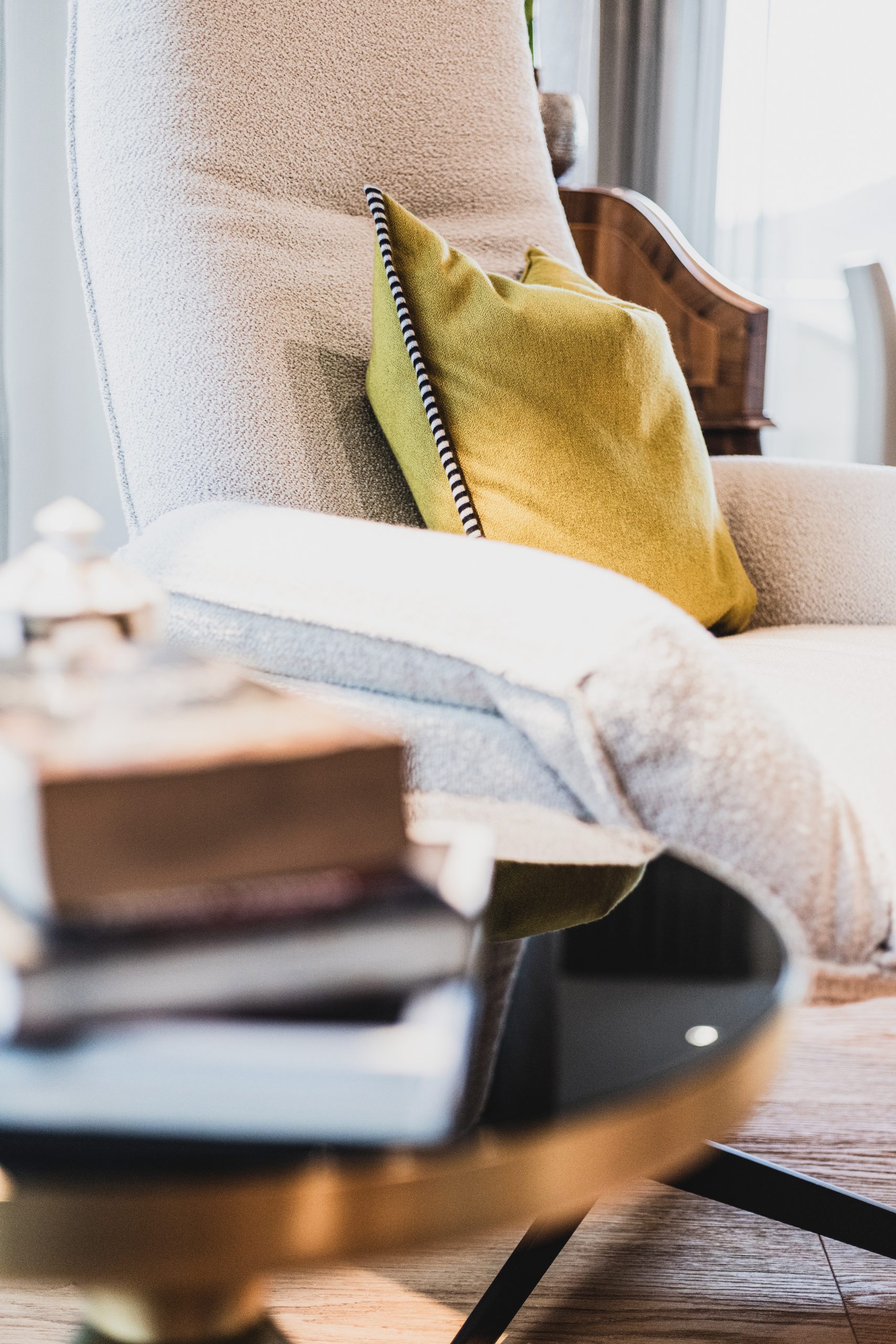 Warme, gemütliche Bouclé-Möbel in neutralen Stoffen schaffen eine einladende Wohnatmosphäre. Akzentfarben setzen elegante Vollton-Kissen in hochwertigen, kontrastierenden Stoffen, die dem Raum Tiefe, Charakter und moderne Innenarchitektur-Qualität verleihen.