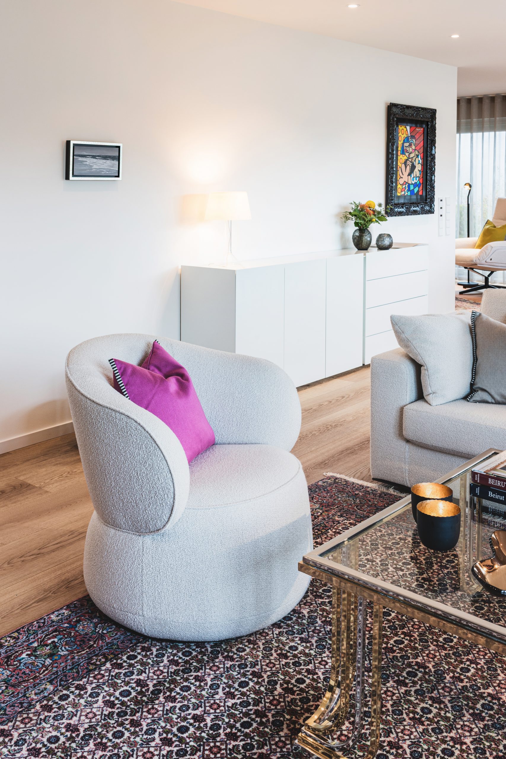 Warme, gemütliche Bouclé-Möbel in neutralen Stoffen schaffen eine einladende Wohnatmosphäre. Akzentfarben setzen elegante Vollton-Kissen in hochwertigen, kontrastierenden Stoffen, die dem Raum Tiefe, Charakter und moderne Innenarchitektur-Qualität verleihen.